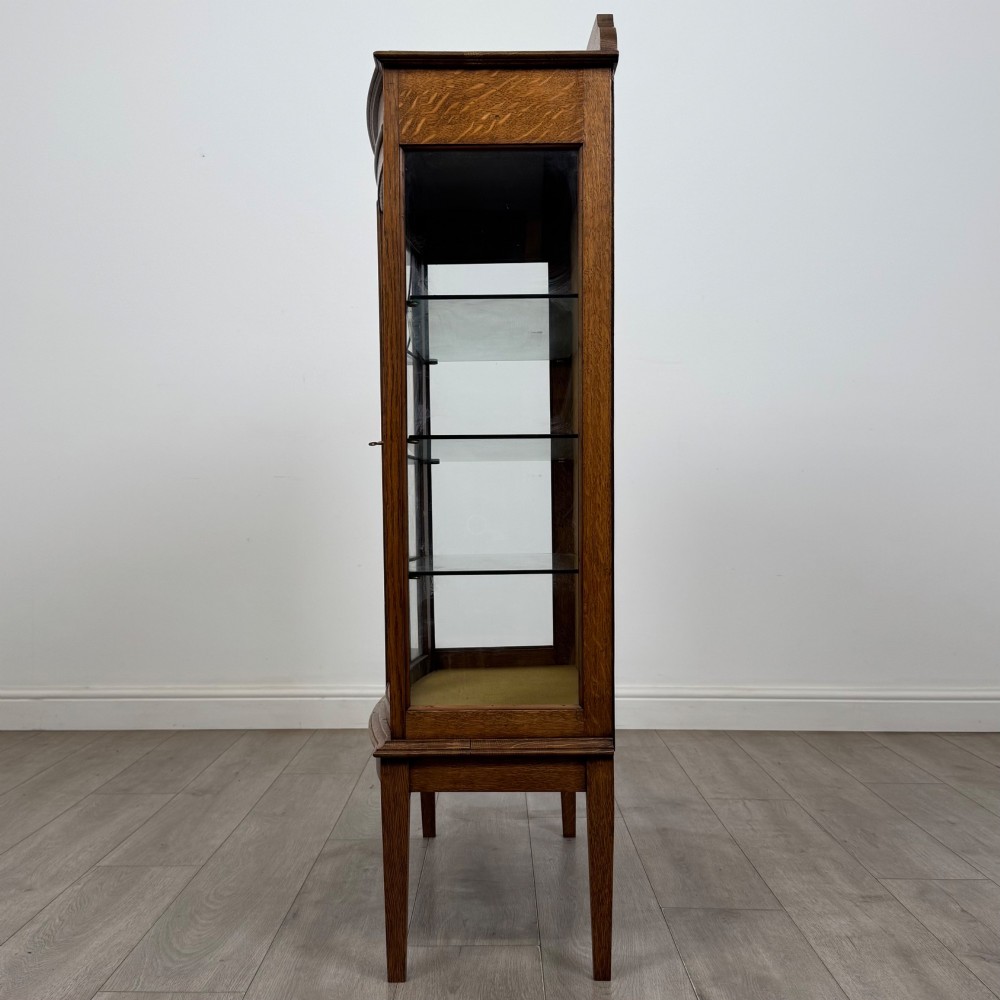 An Edwardian oak display cabinet with double leaded glass doors and square tapered legs. View IV