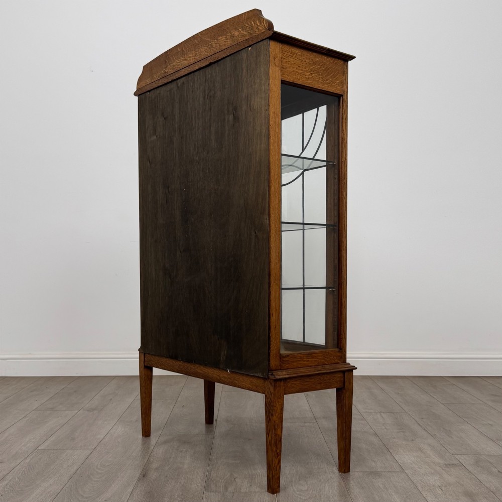 An Edwardian oak display cabinet with double leaded glass doors and square tapered legs. View VII