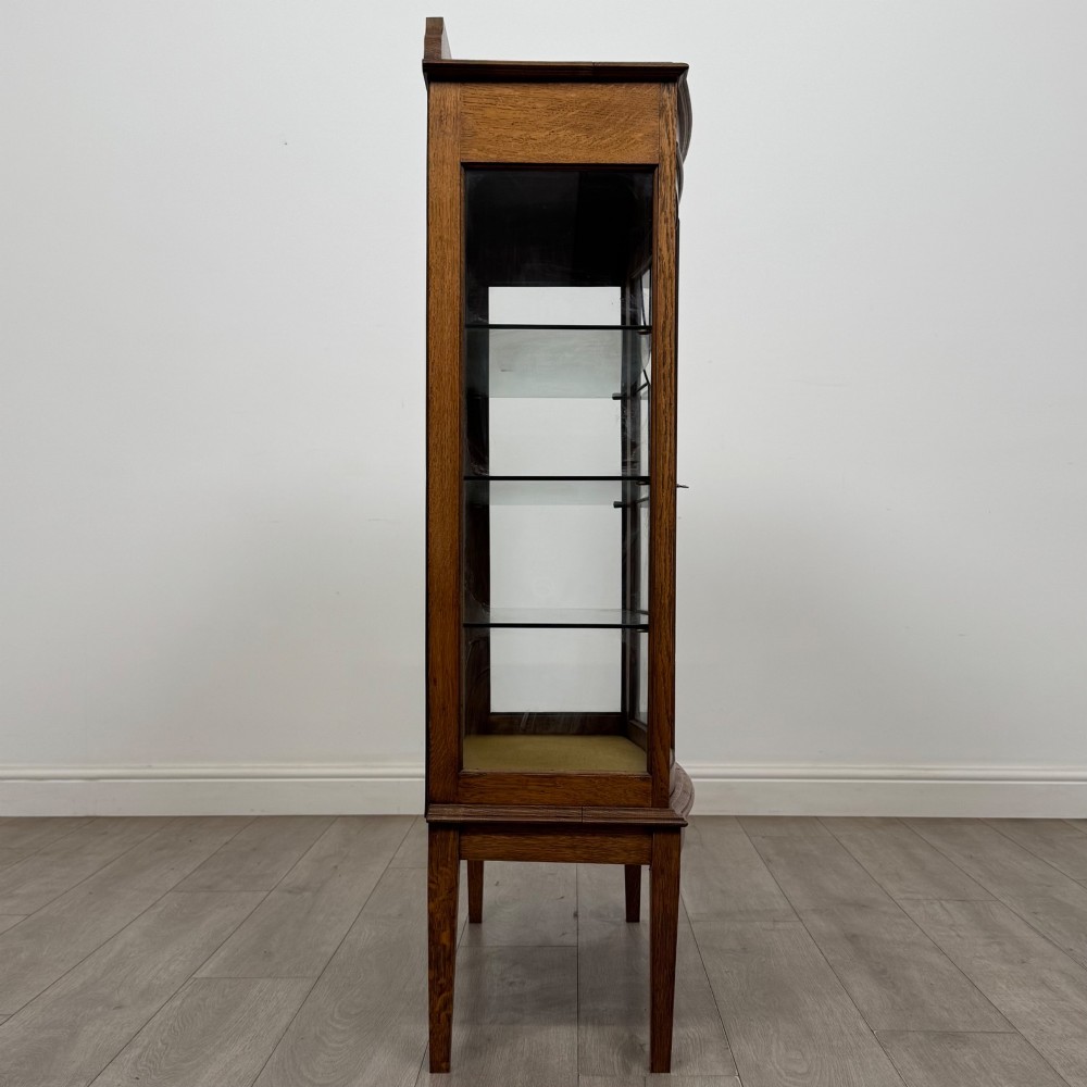 An Edwardian oak display cabinet with double leaded glass doors and square tapered legs. View VIII