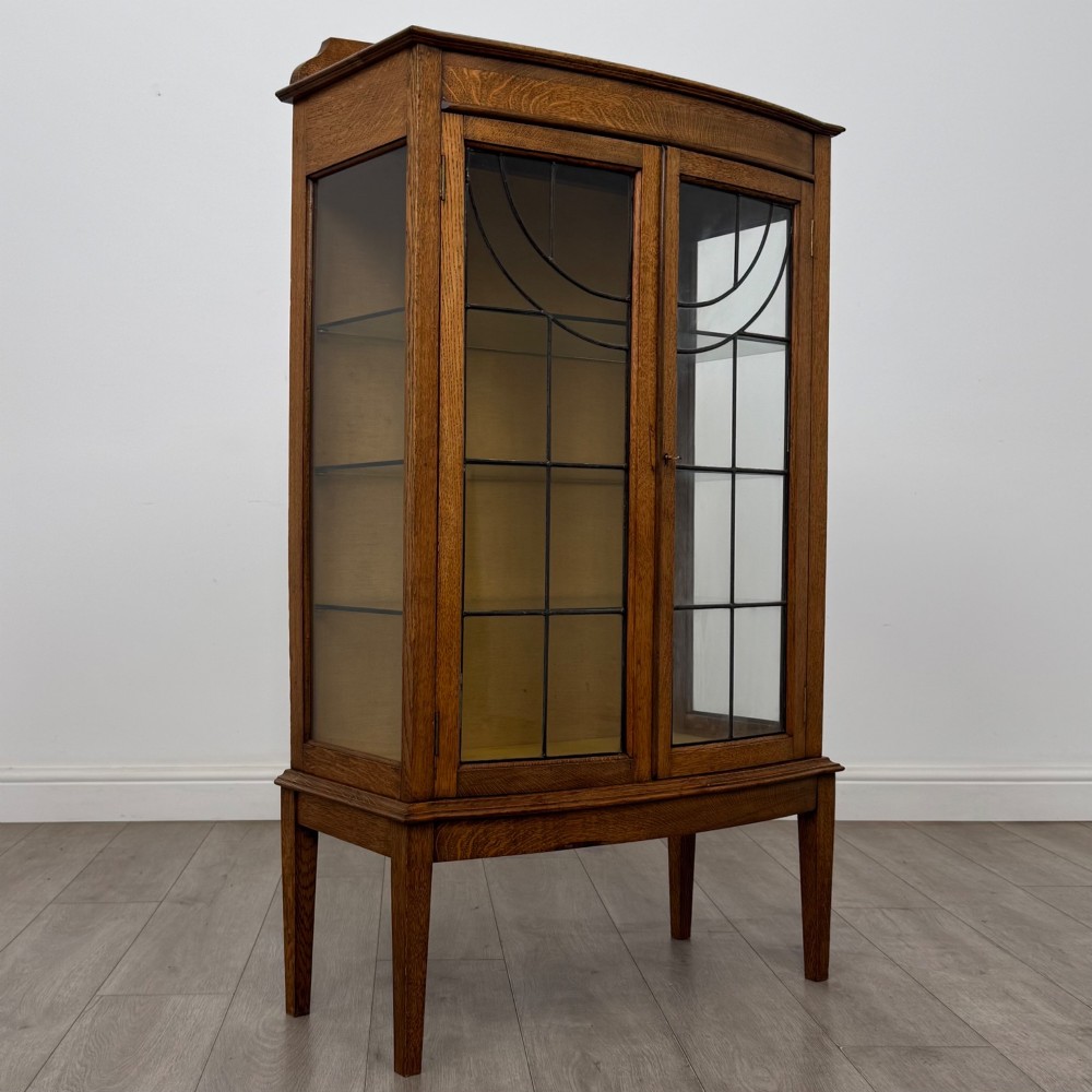An Edwardian oak display cabinet with double leaded glass doors and square tapered legs. View IX