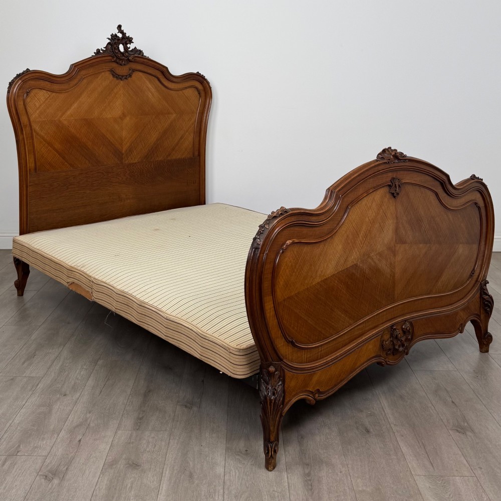 A 19th-century French walnut double bed featuring a carved crest headboard, matching footboard with parquetry panels, and short cabriole legs. View II