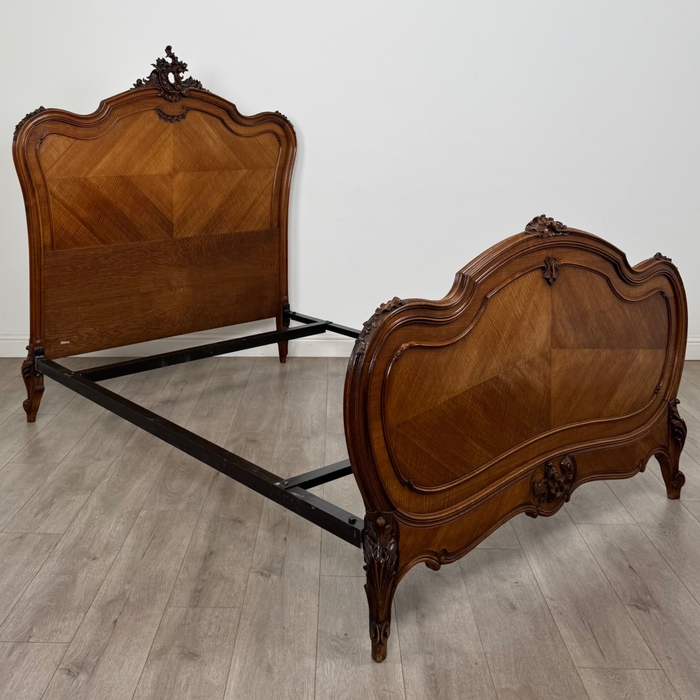 A 19th-century French walnut double bed featuring a carved crest headboard, matching footboard with parquetry panels, and short cabriole legs. View III