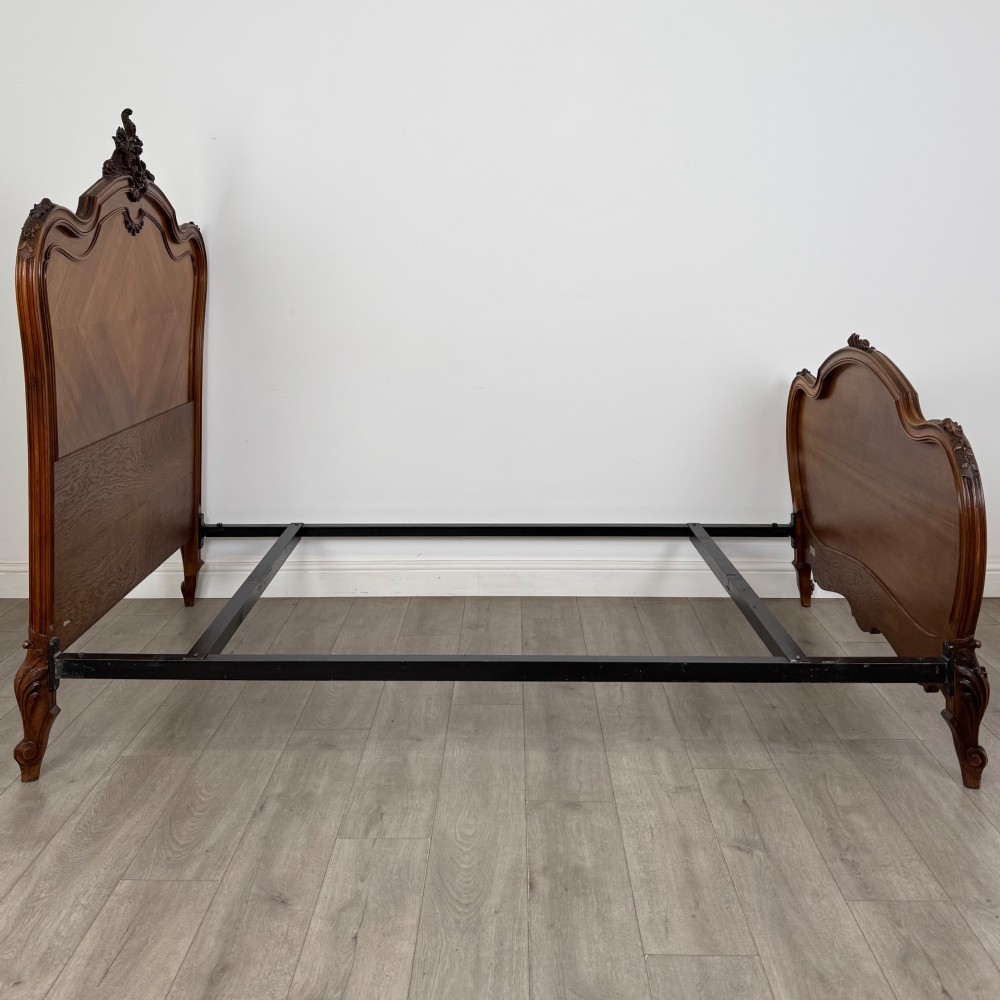 A 19th-century French walnut double bed featuring a carved crest headboard, matching footboard with parquetry panels, and short cabriole legs. View IV