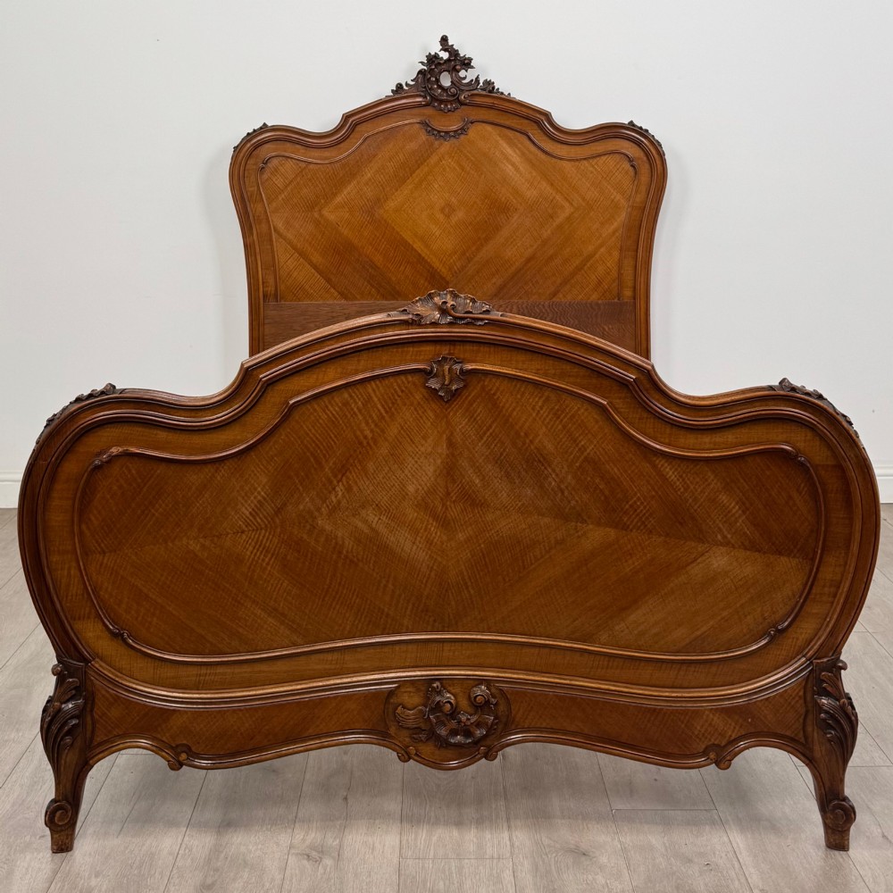 A 19th-century French walnut double bed featuring a carved crest headboard, matching footboard with parquetry panels, and short cabriole legs. View V