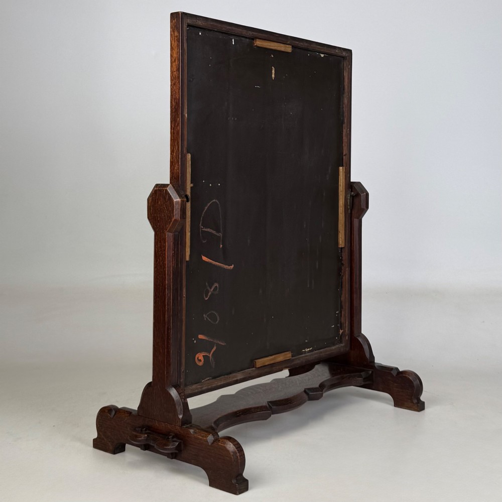 An early 20th-century Arts and Crafts dark oak dressing table mirror set on a shaped base with a swivel frame. View VI