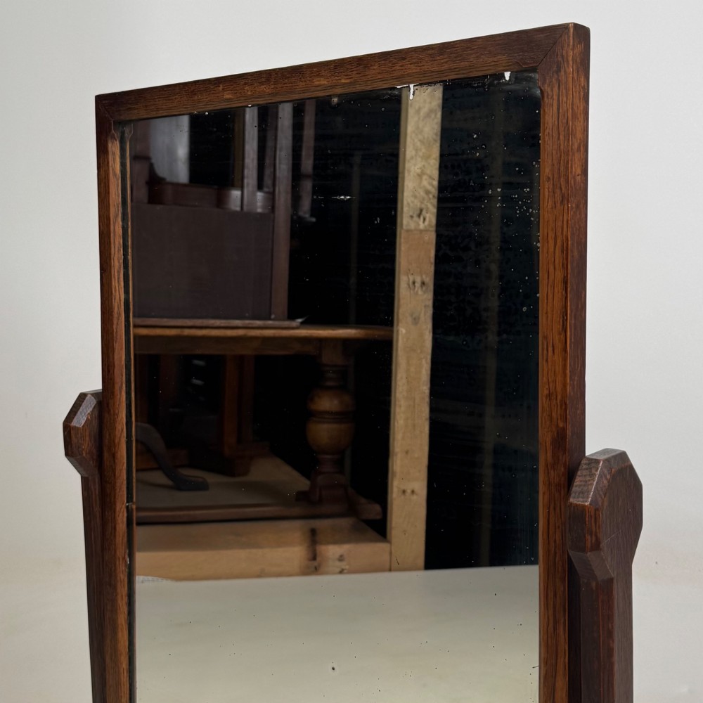 An early 20th-century Arts and Crafts dark oak dressing table mirror set on a shaped base with a swivel frame. View XII