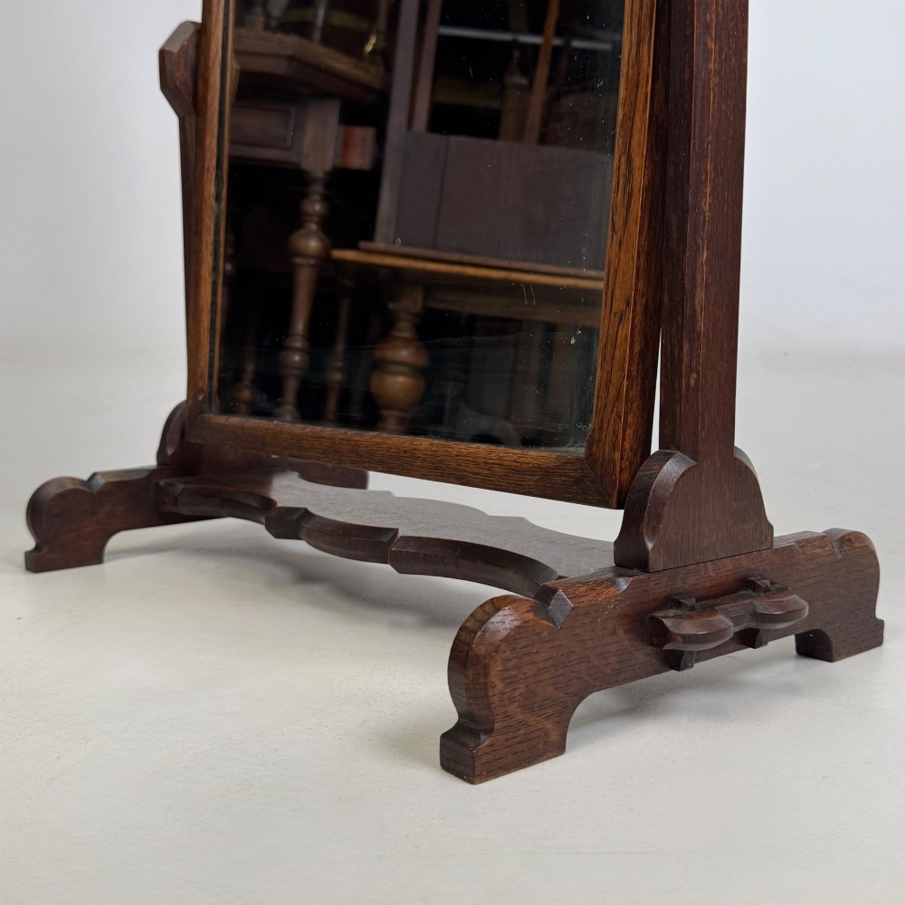 An early 20th-century Arts and Crafts dark oak dressing table mirror set on a shaped base with a swivel frame. View XIII