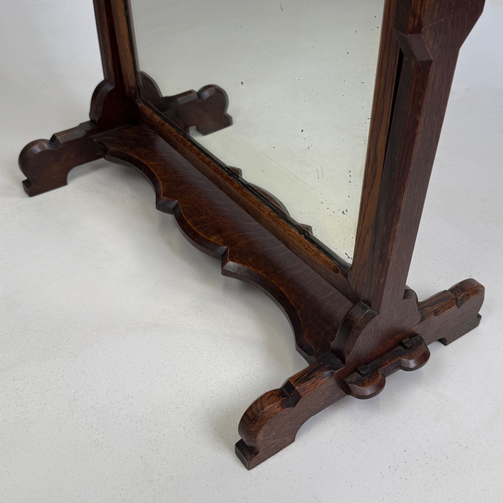 An early 20th-century Arts and Crafts dark oak dressing table mirror set on a shaped base with a swivel frame. View XIV