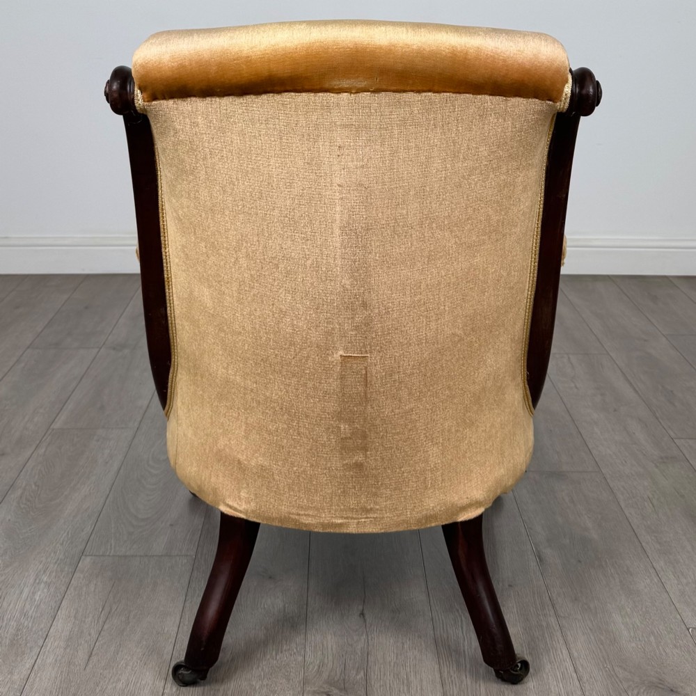 A pair of 19th-century William IV mahogany armchairs upholstered in mustard gold velvet featuring carved scroll arms and turned front legs on brass castors. View V