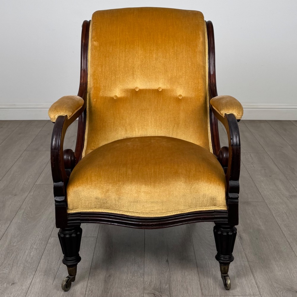 A pair of 19th-century William IV mahogany armchairs upholstered in mustard gold velvet featuring carved scroll arms and turned front legs on brass castors. View IX