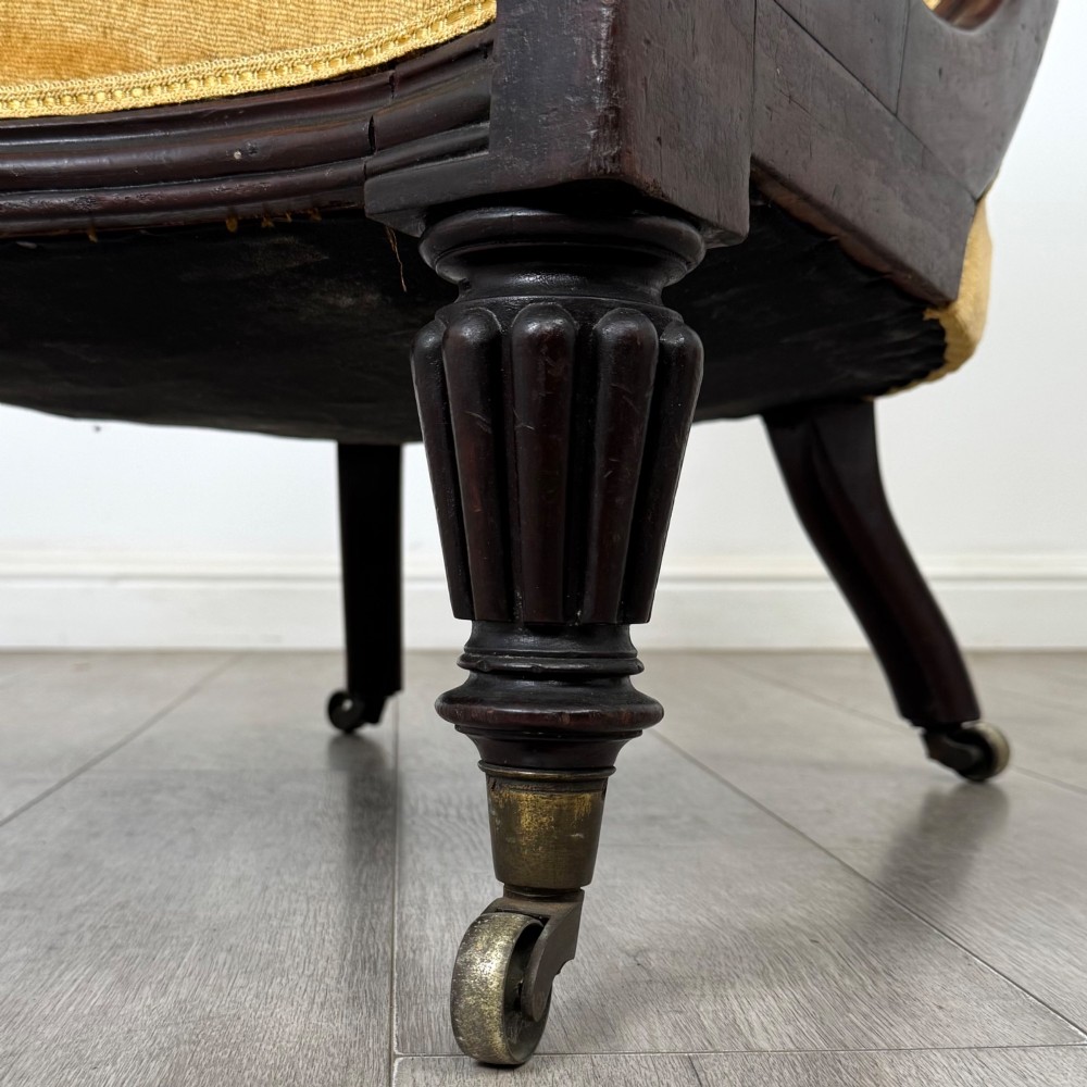 A pair of 19th-century William IV mahogany armchairs upholstered in mustard gold velvet featuring carved scroll arms and turned front legs on brass castors. View XIV