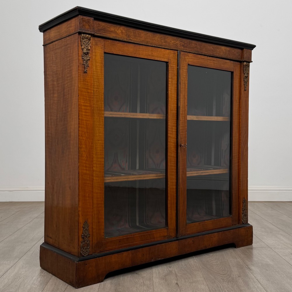 A 19th-century Victorian burr walnut pier cabinet featuring two glass panel doors, brass mounts, marquetry inlay, and a plinth base. View IX