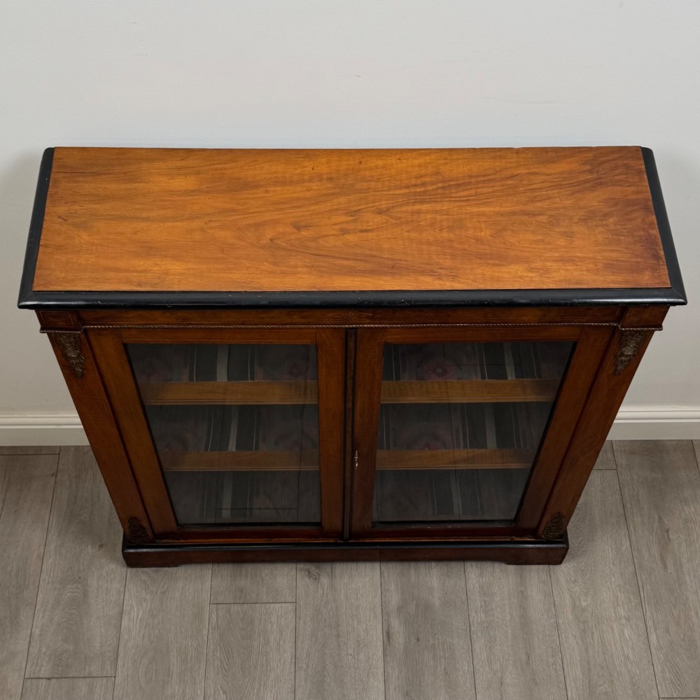 A 19th-century Victorian burr walnut pier cabinet featuring two glass panel doors, brass mounts, marquetry inlay, and a plinth base. View X