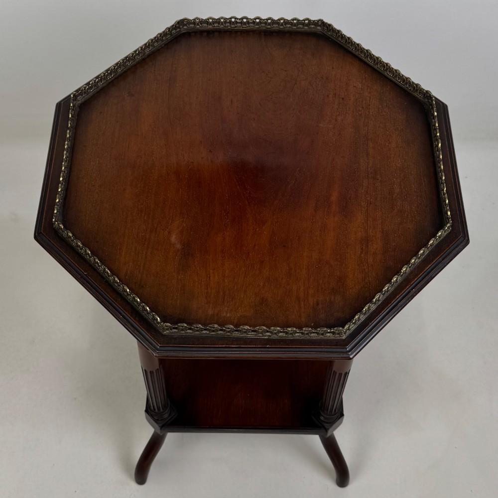 A 19th-century mahogany octagonal side table featuring a brass gallery rail, fluted turned legs, an undertier shelf, and splayed feet. View VIII