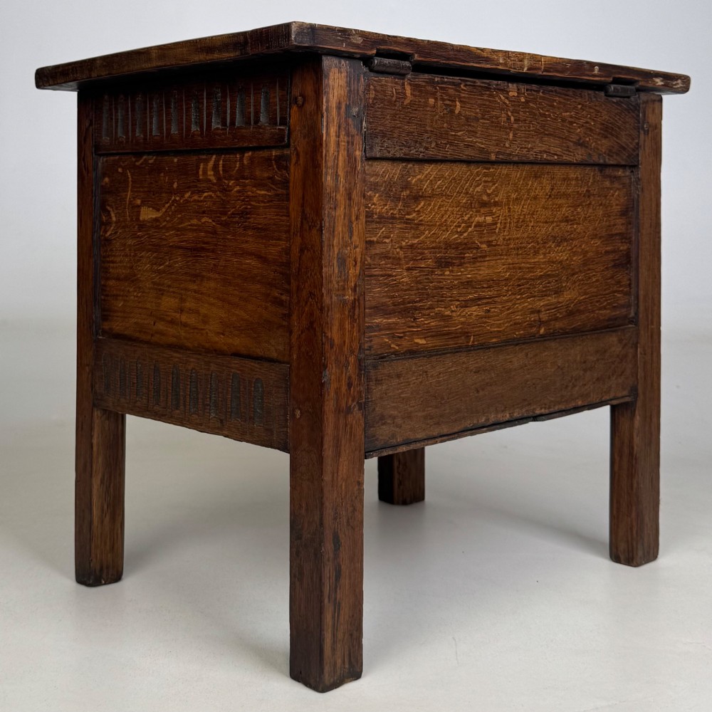 An 18th-century small oak coffer chest featuring carved vertical fluting along the top and bottom rails, a central decorative brass escutcheon, and straight squared legs. View IV