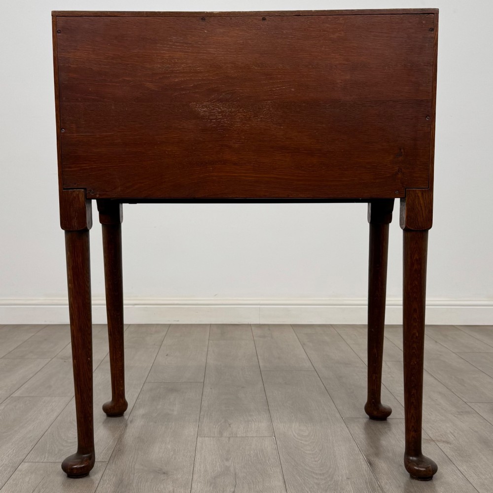 A golden oak slant-front writing bureau standing on four slender legs with pad feet, featuring a single lower drawer with drop handles and a hinged writing slope. View VI
