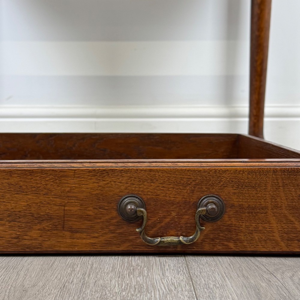 A golden oak slant-front writing bureau standing on four slender legs with pad feet, featuring a single lower drawer with drop handles and a hinged writing slope. View XIII