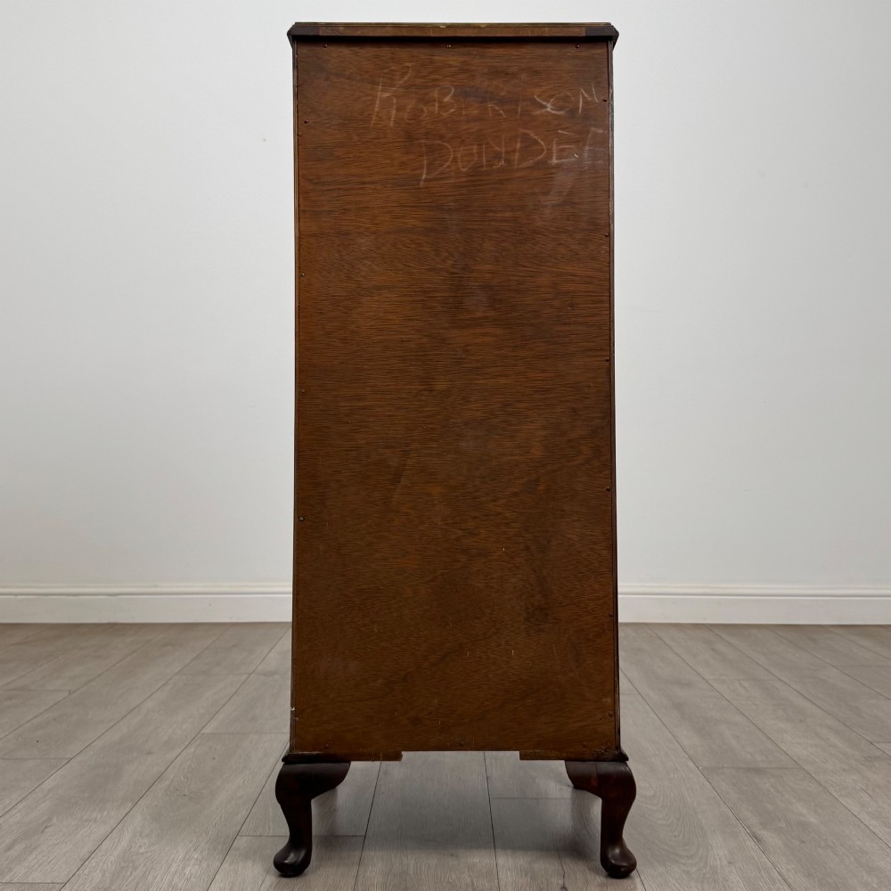 A tall, narrow dark brown burr walnut chest of drawers featuring brass handles and carved cabriole legs. View V