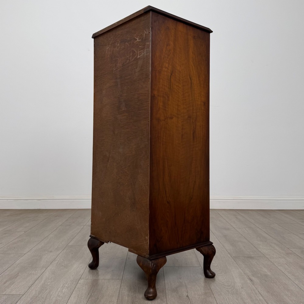 A tall, narrow dark brown burr walnut chest of drawers featuring brass handles and carved cabriole legs. View VI