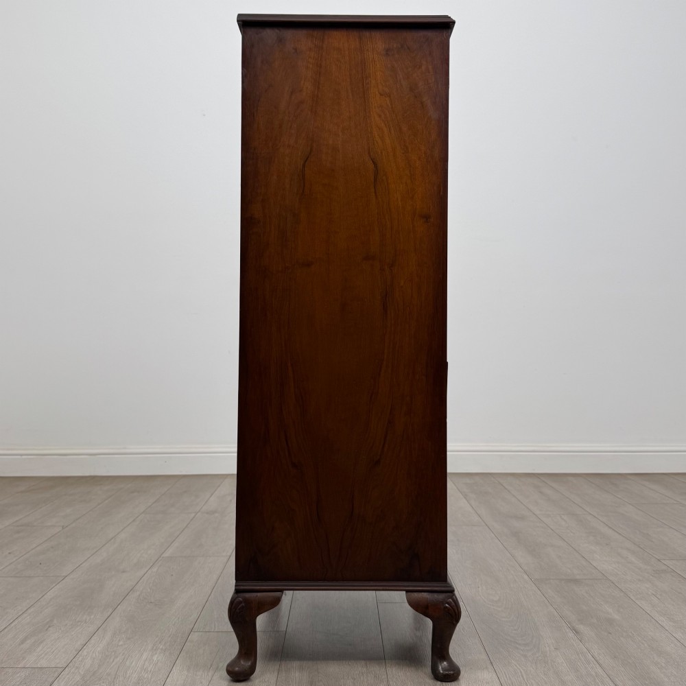 A tall, narrow dark brown burr walnut chest of drawers featuring brass handles and carved cabriole legs. View VII