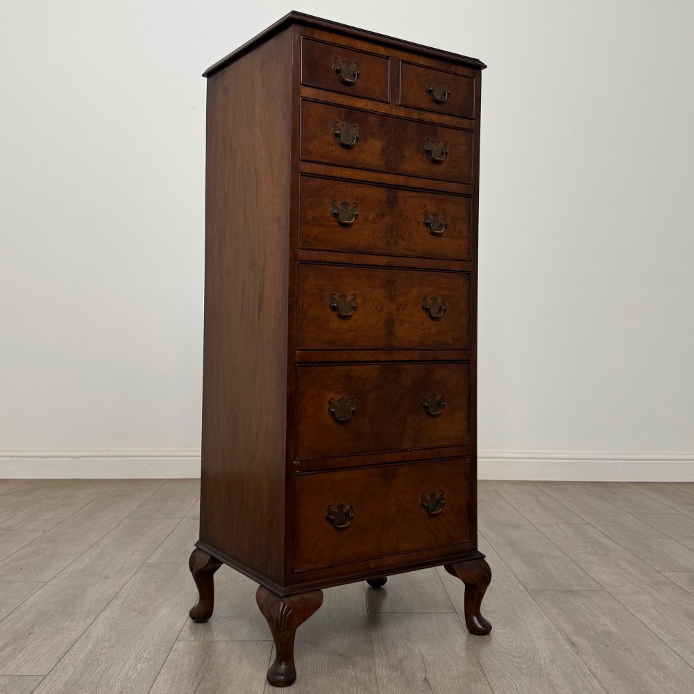 A tall, narrow dark brown burr walnut chest of drawers featuring brass handles and carved cabriole legs. View VIII