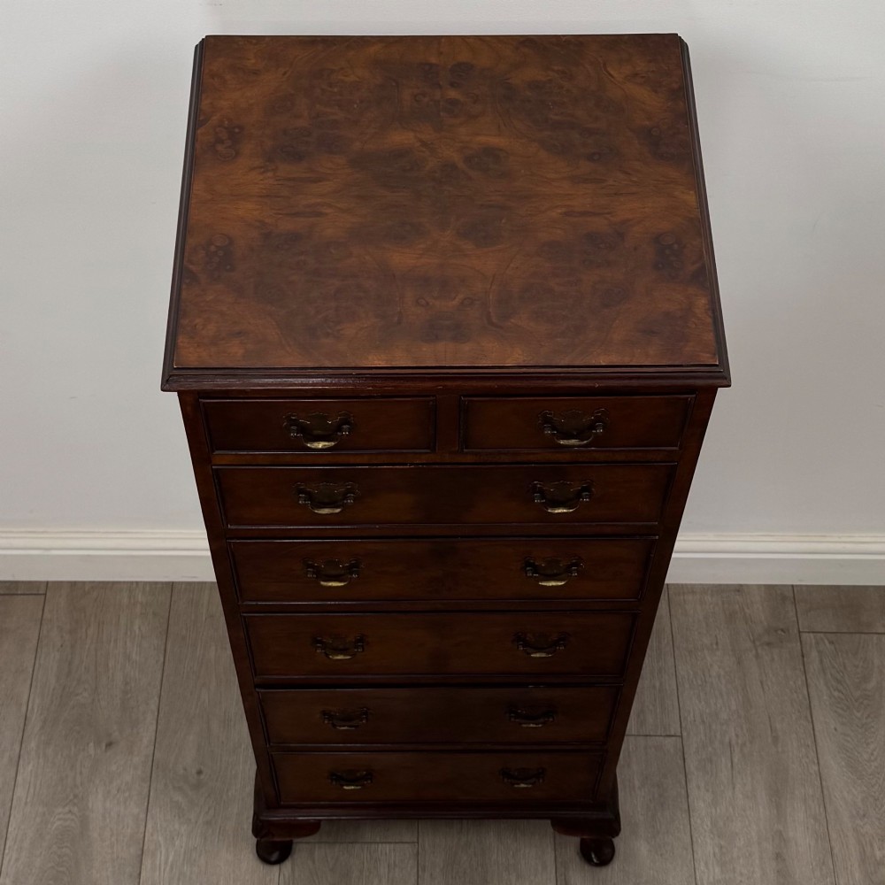 A tall, narrow dark brown burr walnut chest of drawers featuring brass handles and carved cabriole legs. View IX