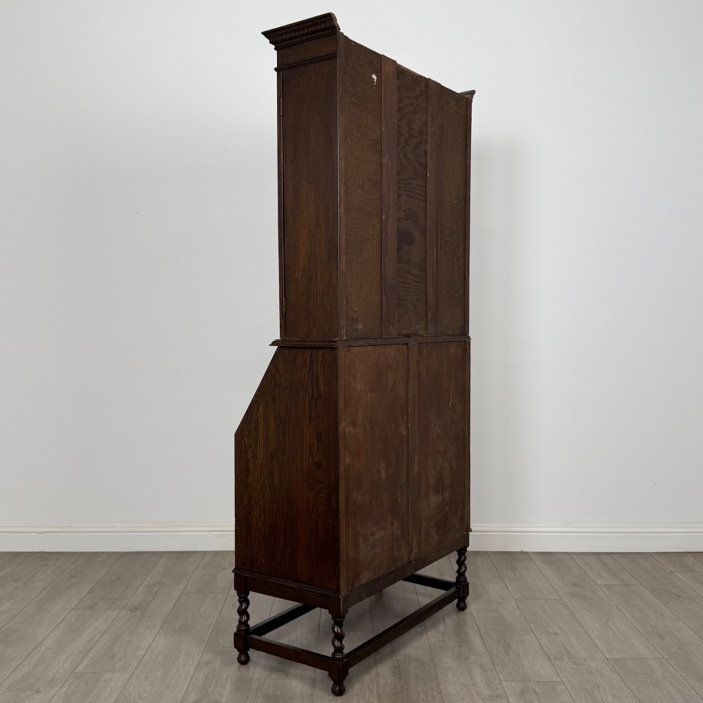 A tall 20th-century Jacobean Revival dark oak bureau bookcase with a leaded glass cabinet above a slant-front writing desk and three lower drawers. View VI