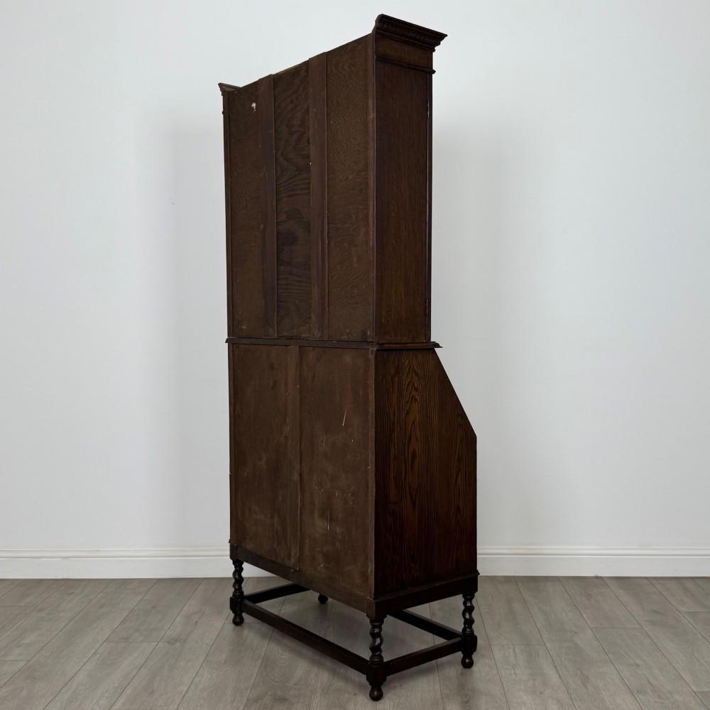 A tall 20th-century Jacobean Revival dark oak bureau bookcase with a leaded glass cabinet above a slant-front writing desk and three lower drawers. View VIII
