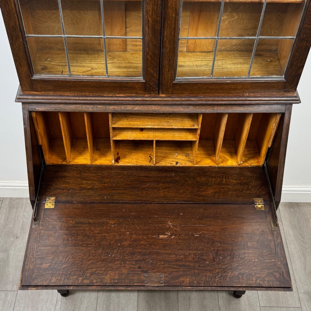 A tall 20th-century Jacobean Revival dark oak bureau bookcase with a leaded glass cabinet above a slant-front writing desk and three lower drawers. View XII