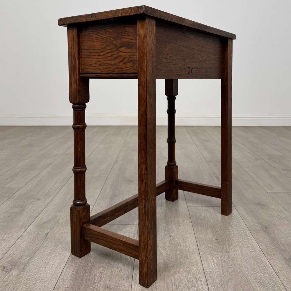 A small dark oak side table featuring a single drawer with a brass handle, turned front legs, and lower stretchers. View IV
