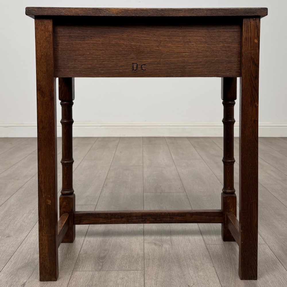 A small dark oak side table featuring a single drawer with a brass handle, turned front legs, and lower stretchers. View V
