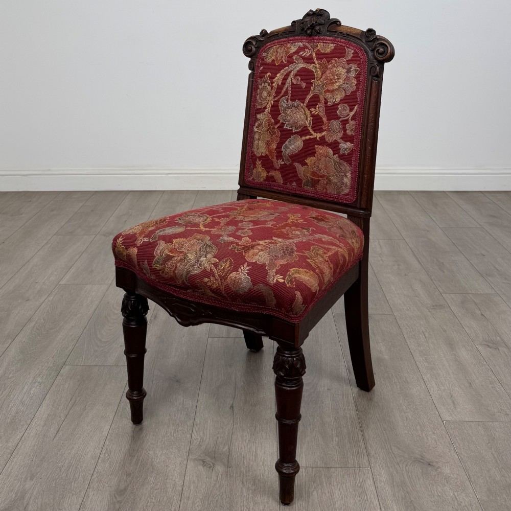 A set of six antique 19th-century Victorian oak dining chairs featuring carved crest rails and red patterned fabric upholstery. View II