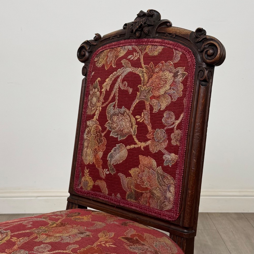 A set of six antique 19th-century Victorian oak dining chairs featuring carved crest rails and red patterned fabric upholstery. View IV