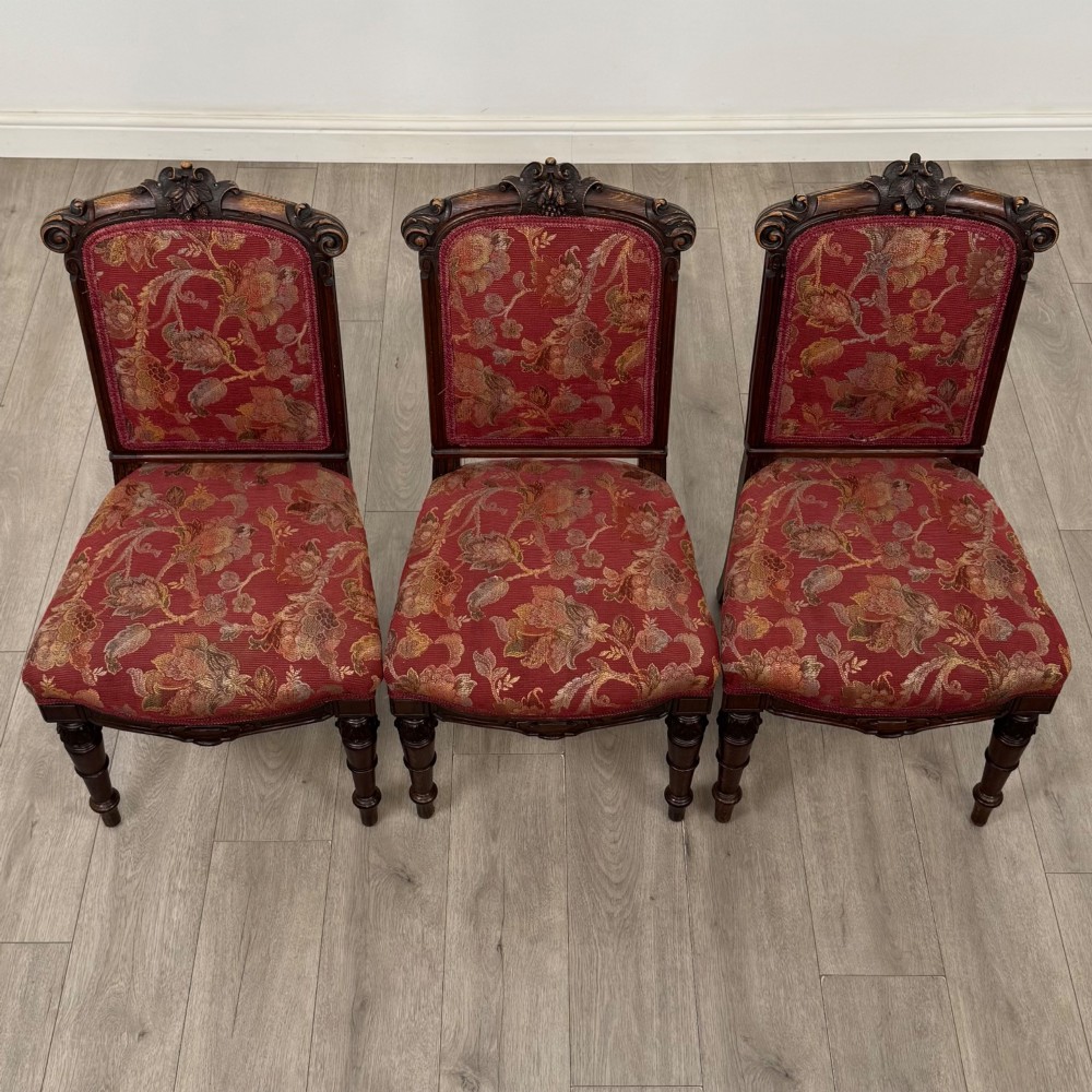 A set of six antique 19th-century Victorian oak dining chairs featuring carved crest rails and red patterned fabric upholstery. View VII