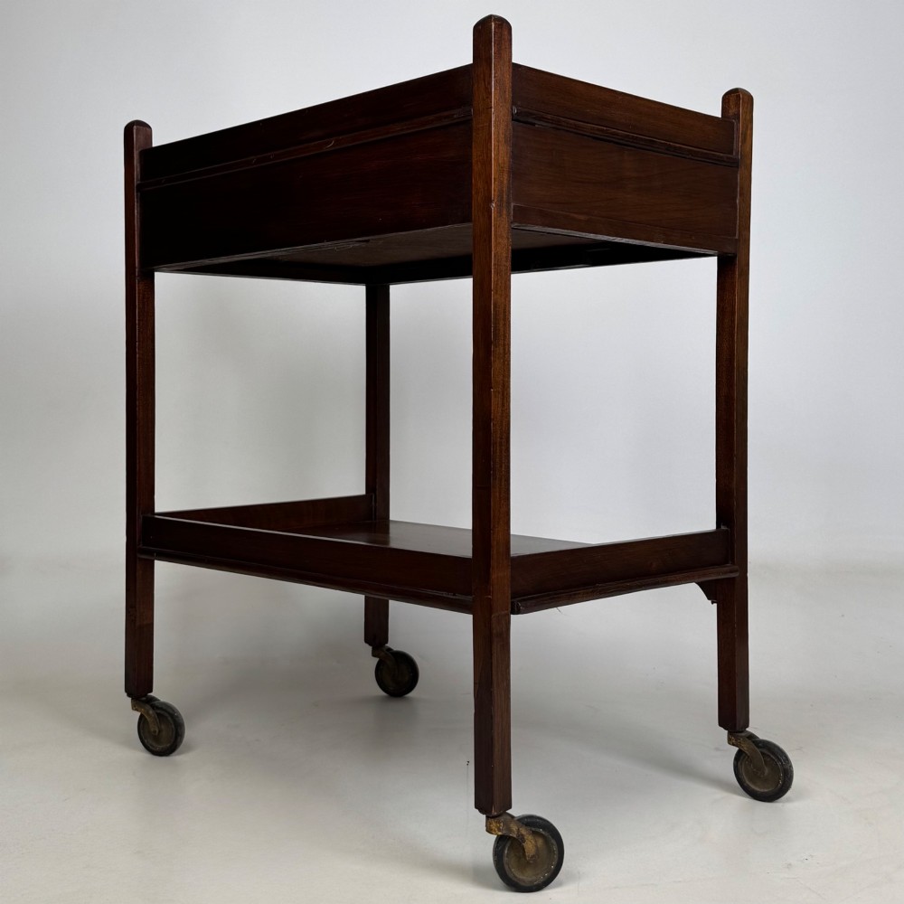 A two-tier dark mahogany Georgian style tea trolley featuring a single drawer with a brass ring handle and four castor wheels. View IV