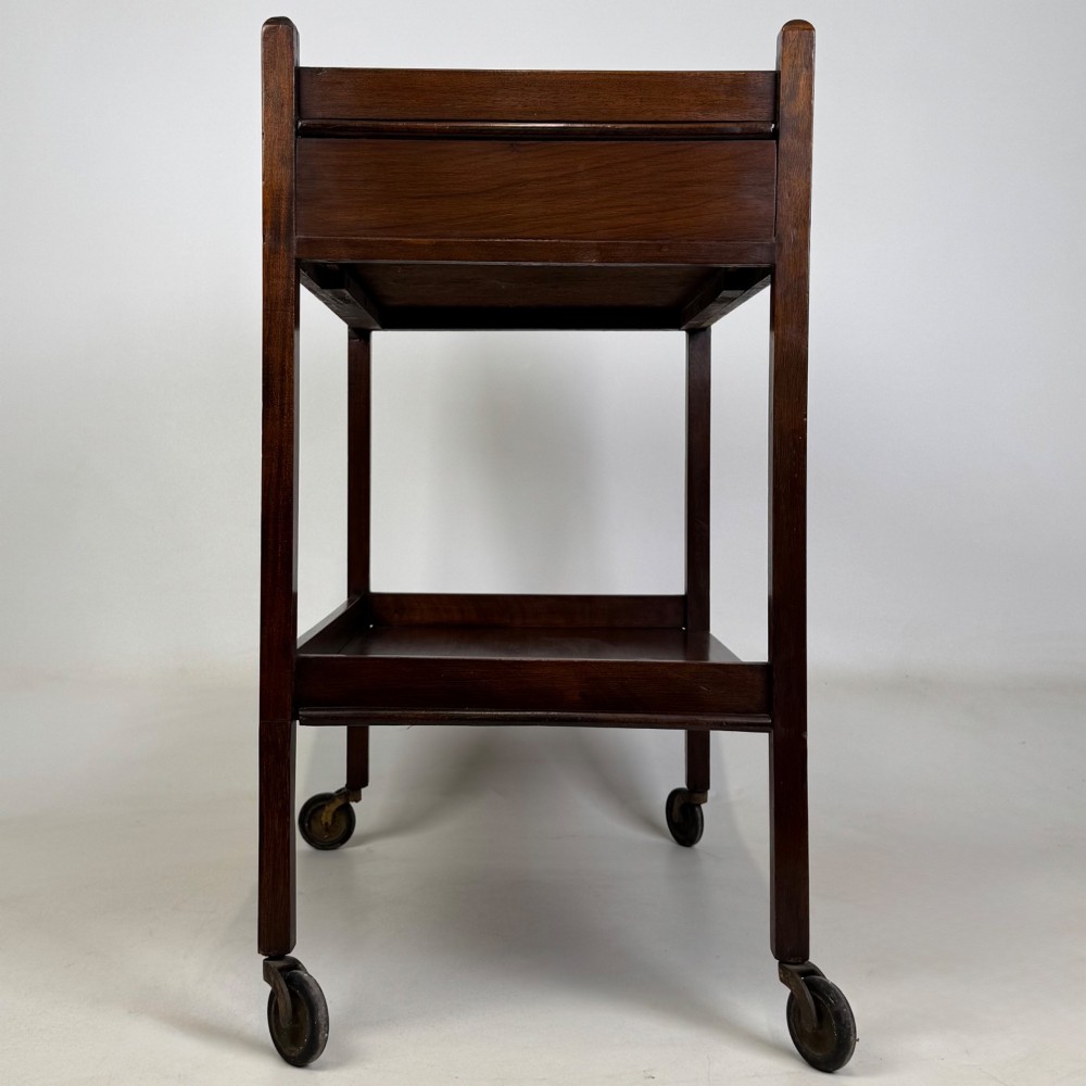 A two-tier dark mahogany Georgian style tea trolley featuring a single drawer with a brass ring handle and four castor wheels. View V