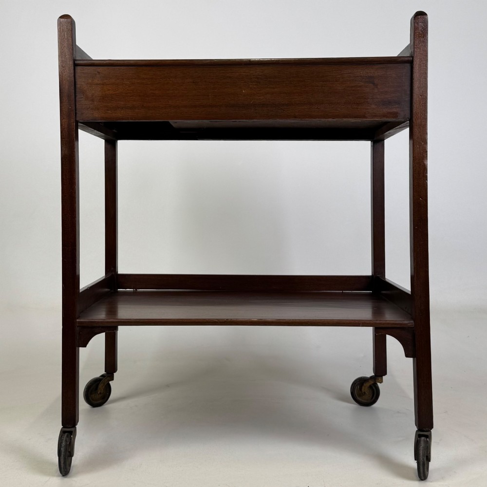 A two-tier dark mahogany Georgian style tea trolley featuring a single drawer with a brass ring handle and four castor wheels. View VII