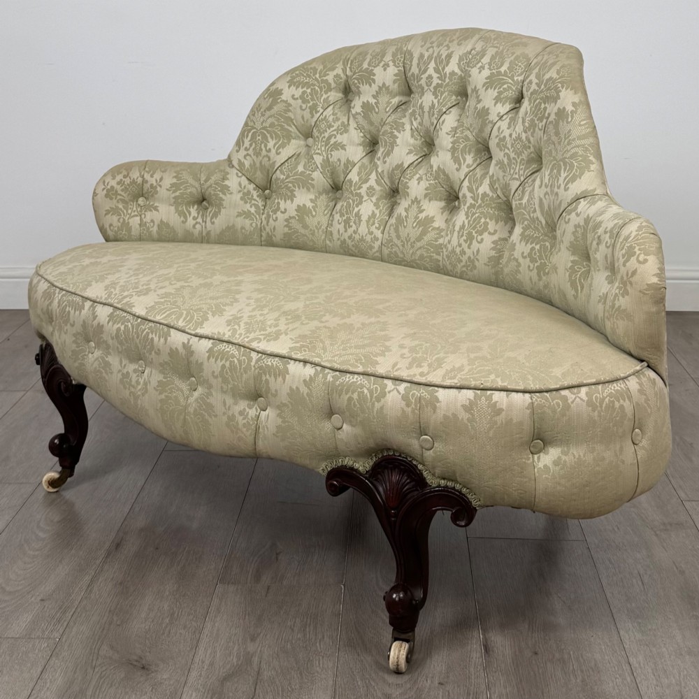 A 19th-century Victorian settee upholstered in sage green patterned damask with button-tufting and carved dark mahogany legs on ceramic castors. View II