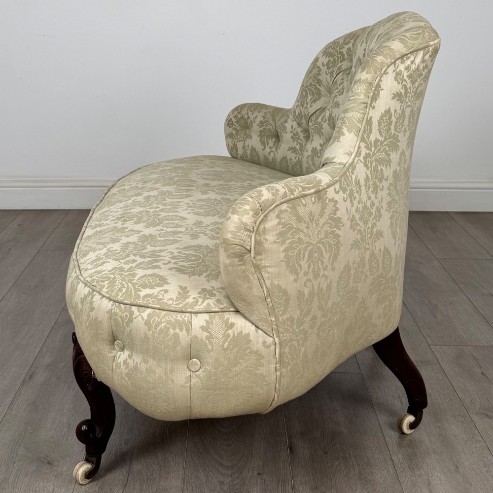 A 19th-century Victorian settee upholstered in sage green patterned damask with button-tufting and carved dark mahogany legs on ceramic castors. View III