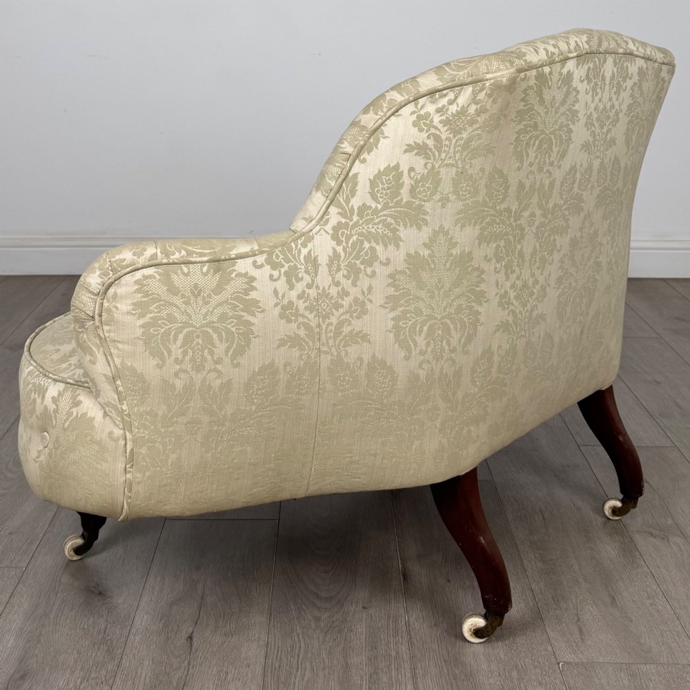 A 19th-century Victorian settee upholstered in sage green patterned damask with button-tufting and carved dark mahogany legs on ceramic castors. View IV