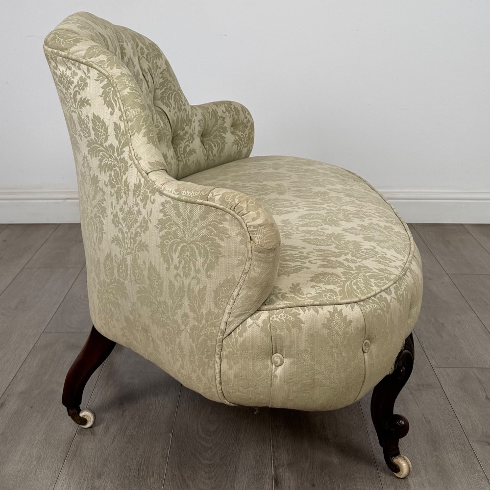 A 19th-century Victorian settee upholstered in sage green patterned damask with button-tufting and carved dark mahogany legs on ceramic castors. View VII