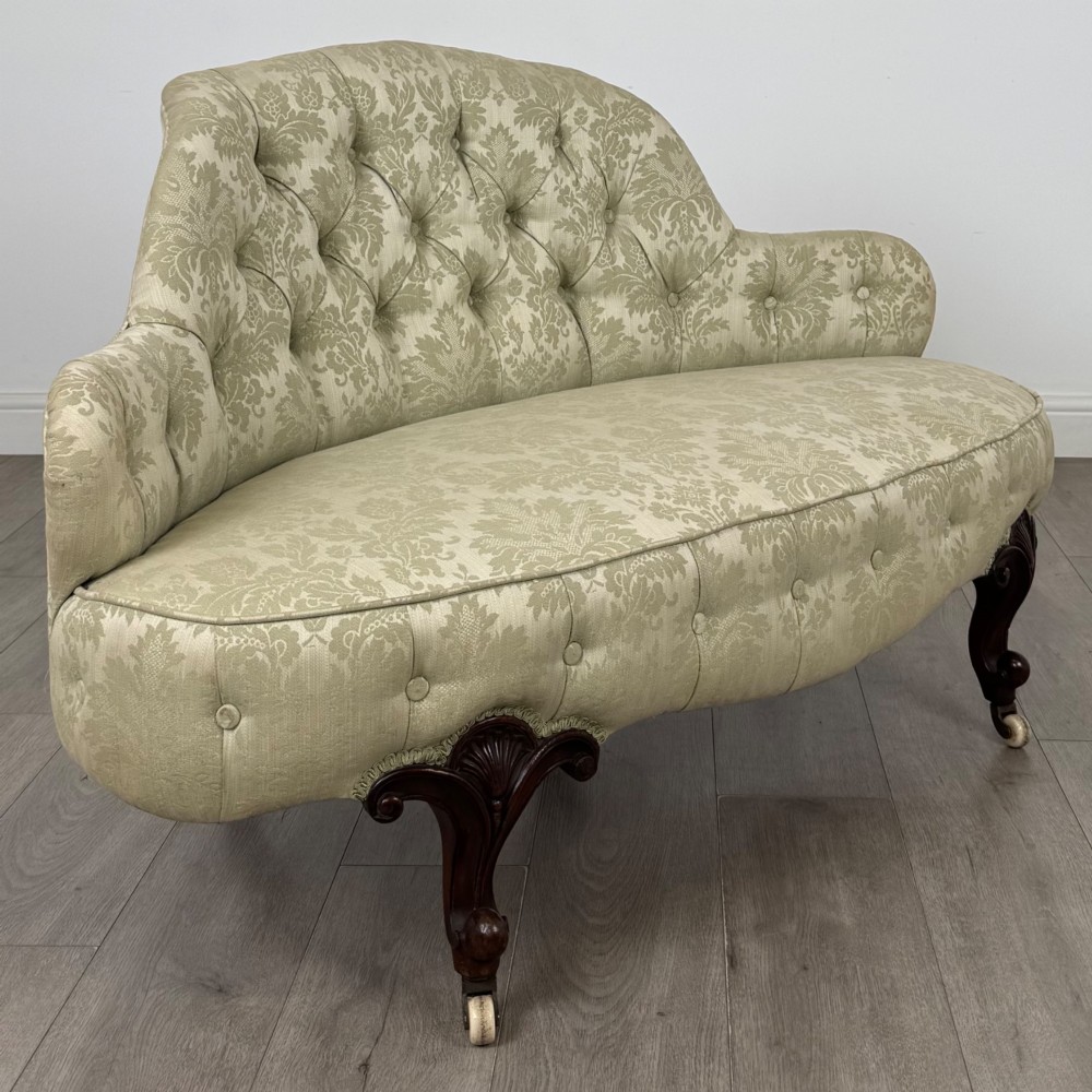 A 19th-century Victorian settee upholstered in sage green patterned damask with button-tufting and carved dark mahogany legs on ceramic castors. View VIII