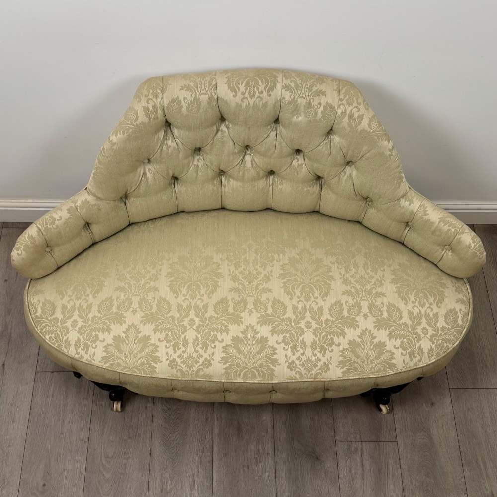 A 19th-century Victorian settee upholstered in sage green patterned damask with button-tufting and carved dark mahogany legs on ceramic castors. View IX