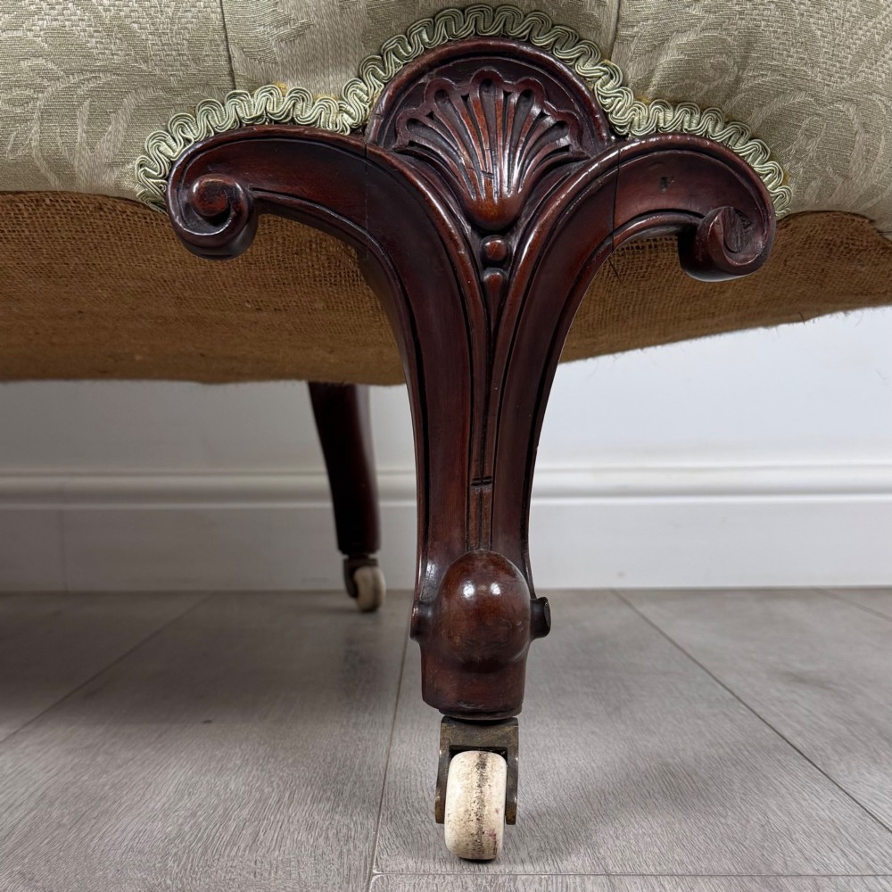 A 19th-century Victorian settee upholstered in sage green patterned damask with button-tufting and carved dark mahogany legs on ceramic castors. View X