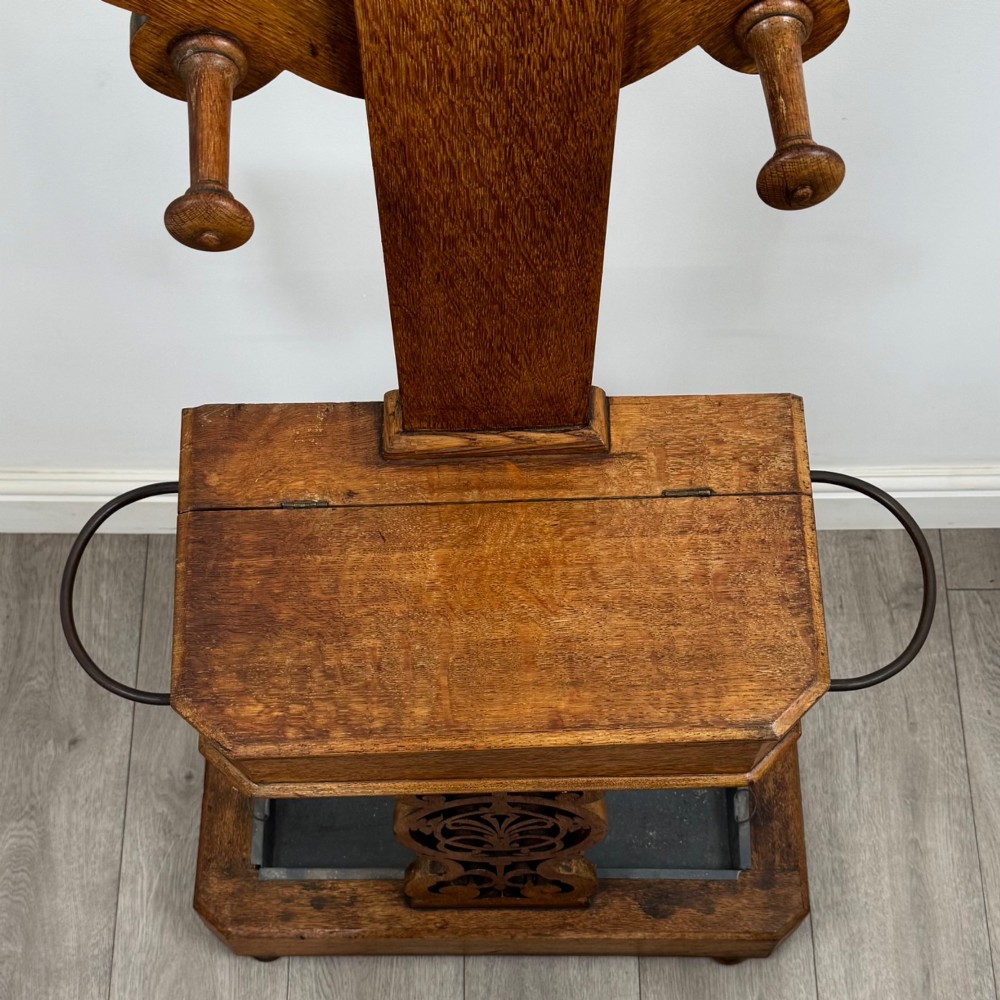 A nineteenth-century Victorian mahogany hall stand featuring coat pegs, a central circular mirror, metal umbrella loops, carved lower scrollwork, and a base drip tray. View IX