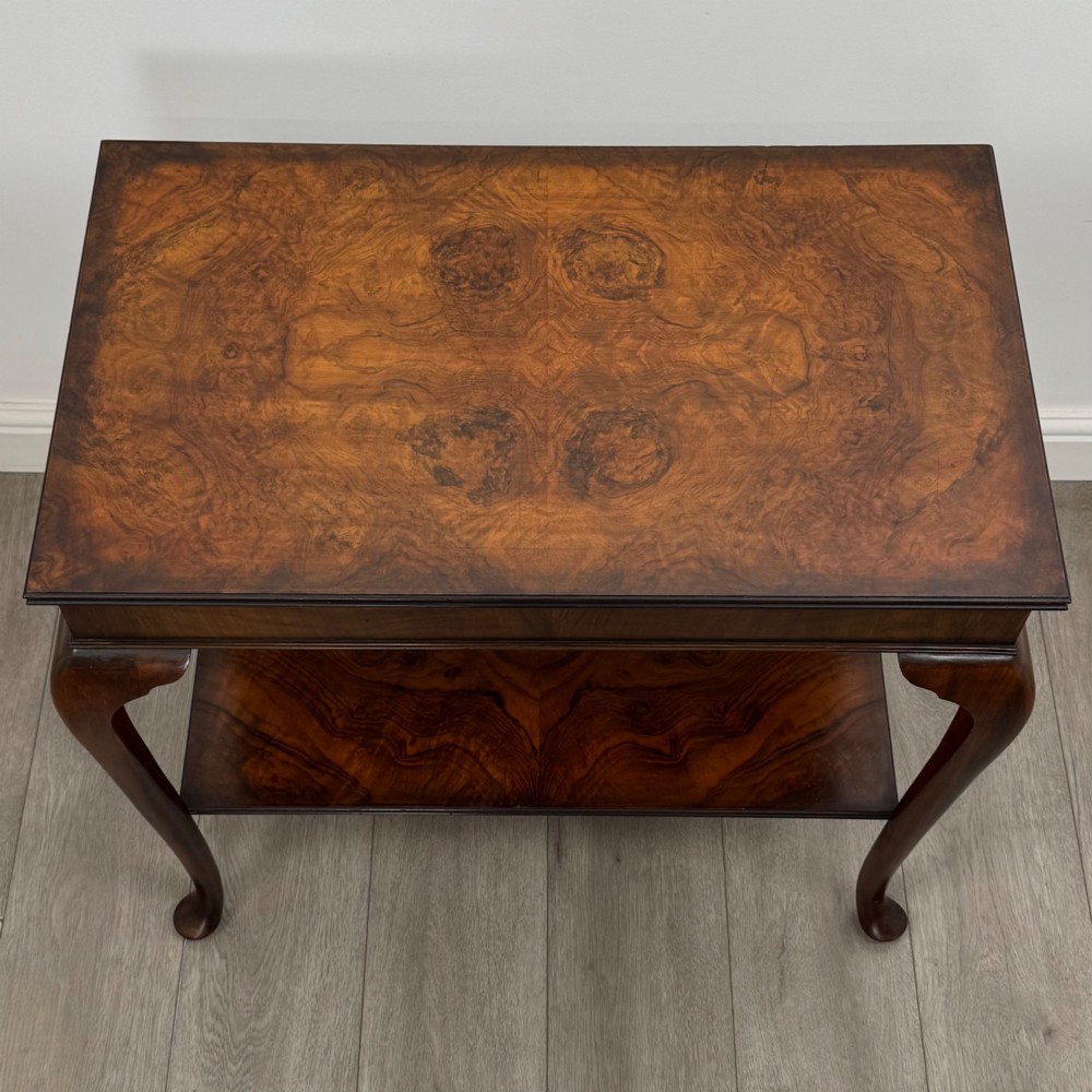 An Edwardian burr walnut side table featuring sloped cabriole legs, pad feet, a deep frieze, and a lower undertier shelf. View IX