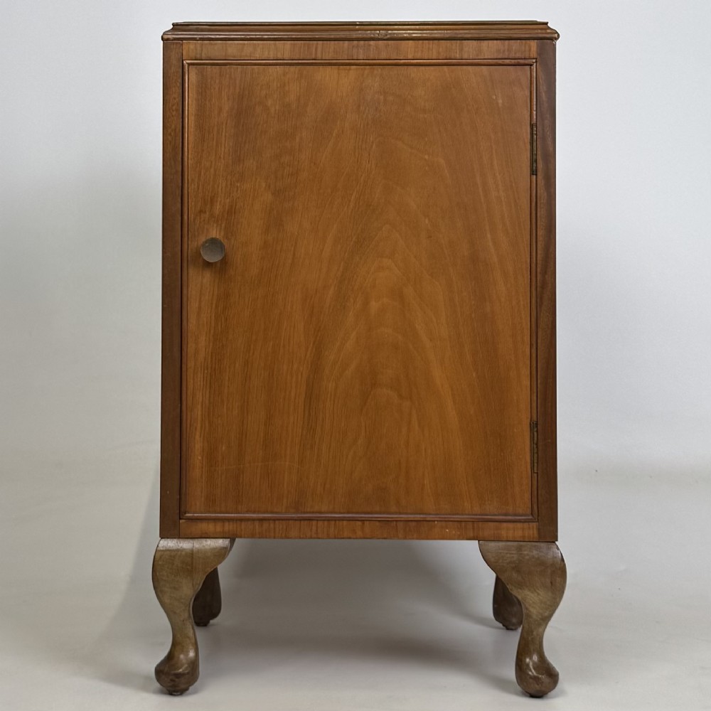 A pair of warm brown walnut bedside cabinets featuring single door cupboards, small round knobs, and carved cabriole legs with pad feet. View II