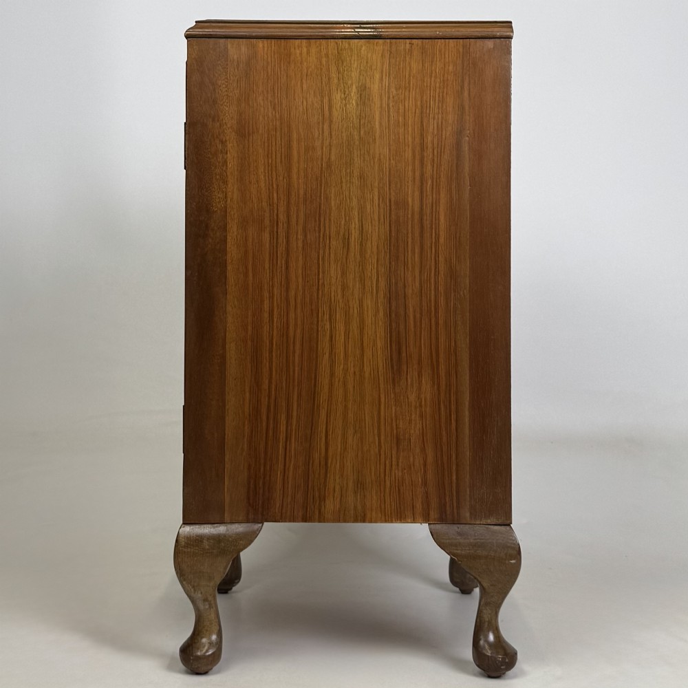 A pair of warm brown walnut bedside cabinets featuring single door cupboards, small round knobs, and carved cabriole legs with pad feet. View V