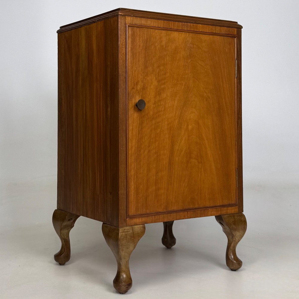 A pair of warm brown walnut bedside cabinets featuring single door cupboards, small round knobs, and carved cabriole legs with pad feet. View X