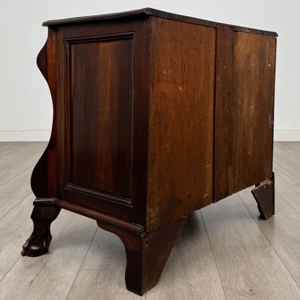A small 20th-century Dutch bombe chest of drawers made from polished brown wood with three drawers, brass handles, and carved claw feet. View IV